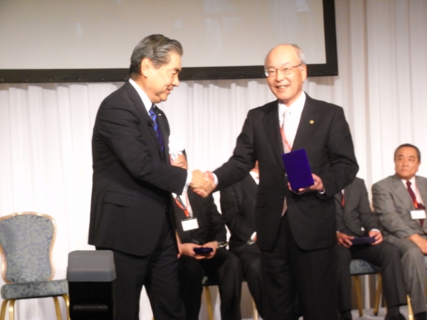 黒田社長から表彰状と記念品を渡される日興商会藤縄健一社長