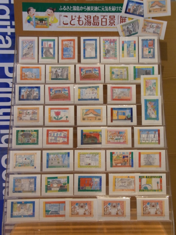 １枚100円、会場では子供たちが描いた絵はがき「こども湯島百景」が義援金付きで販売されている