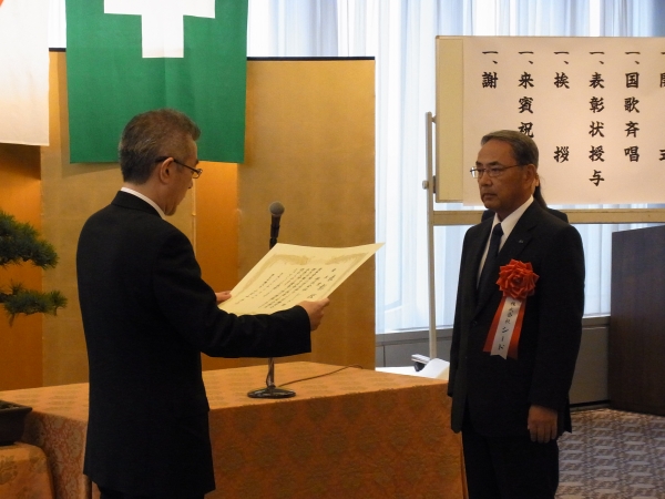 牧義夫厚生労働副大臣から表彰状を授与される西岡靖博相談役