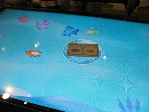 専用のカードに描いた魚のイラストをモニターの上に置くと、魚の絵がモニター水槽の中泳ぎ回る。