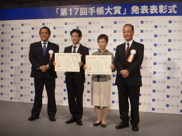 「商品企画部門」を受賞した２人と岡田執行役員、高橋社長