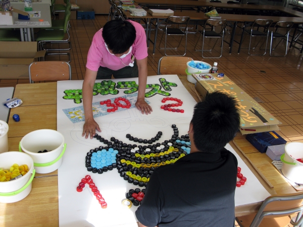 大きな紙にペットボトルのキャップを貼り付けアートを完成させる「エコキャップdeぶんちゃん」