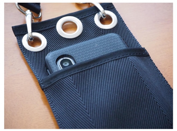 スマートフォンを入れたイメージ。幅約 75 ㎜、高さ約 165 ㎜、厚さ 10mm 程度のものまでポケット に入れられます。金具はナスカンになっており、外せます