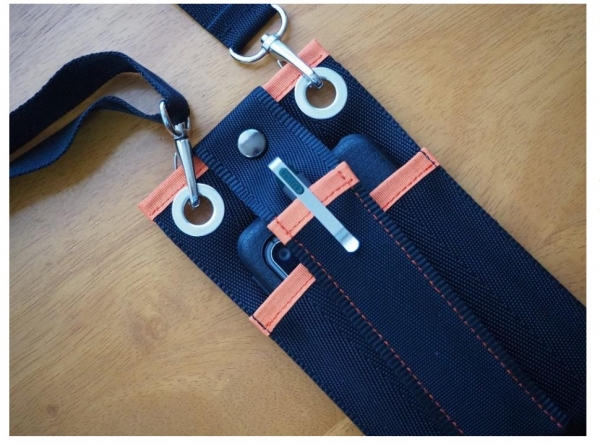 弊社製品であるペネックを、カタ ポケ上部のハトメに接続できます。 このように接続することによって、 スマートフォンなどの内容物が滑 り落ちにくくなります。