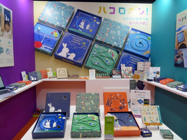 ハコロポン! は、高級感のある「貼箱」に入った「カード式の新しい絵本」。絵柄の入ったカードの溝に、玉を転がしてお話を進める「玩具」と「絵本」が融合した「コロコロあそべる、オハナシばこ」泰清紙器製作所