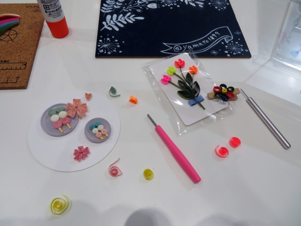 ヤマト「ペーパークイリング」の体験コーナー。｢ペーパークイリング｣は、細長い紙をくるくると巻いてパーツを作り、その組み合わせで花や模様をかたどり、カードやラッピング等を装飾します。紙の色、巻き方やパーツの組み合わせでオリジナル作品が手軽に楽しめる人気のペーパークラフト