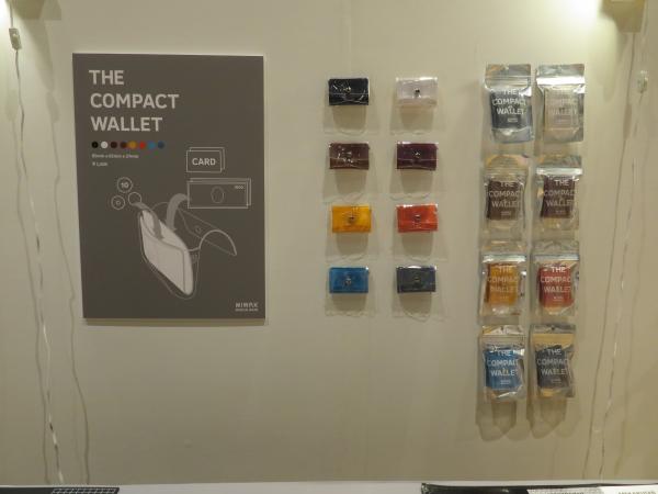 「ザ・コンパクトウォレット（ミニ財布）」は、デスクマットの透明素材と環境に配慮したリサイクルレザーでつくった。水やヨゴレに強いのでアウトドアシーンでも気にせず使用可能。カラーは、ワイト・ブラック・ブラウン・ワイン・イエロー・オレンジ・ターコイズブルー・シーガルブルー